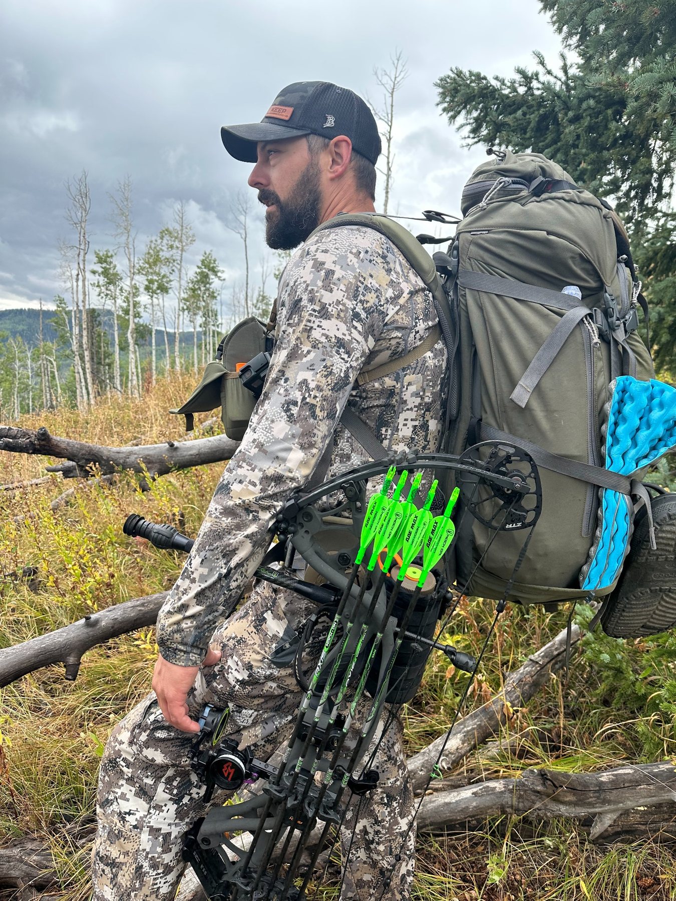 Bowhunter carrying a compound bow and backpack in mountain terrain